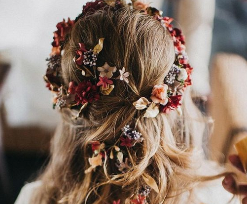 Berry and peach colored flowers woven into brides hair